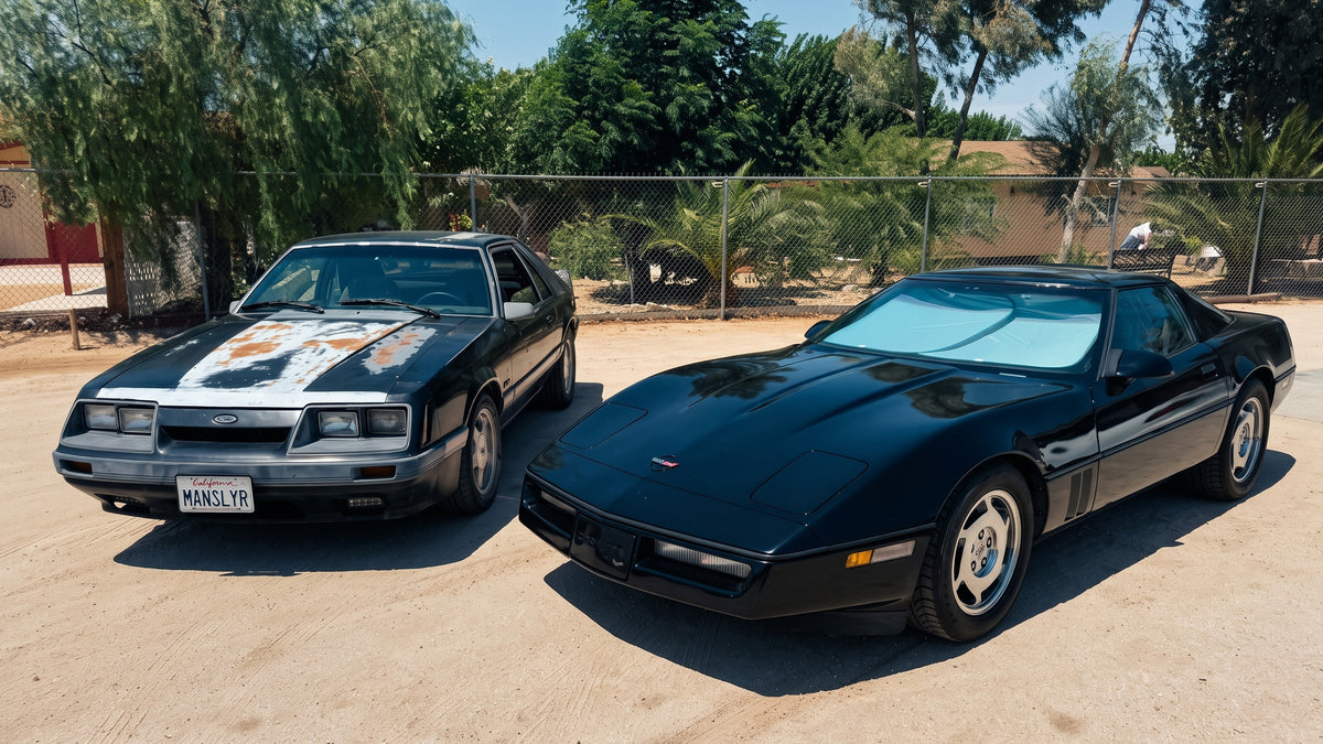 A weathered Ford Mustang and a black Corvette parked side by side.