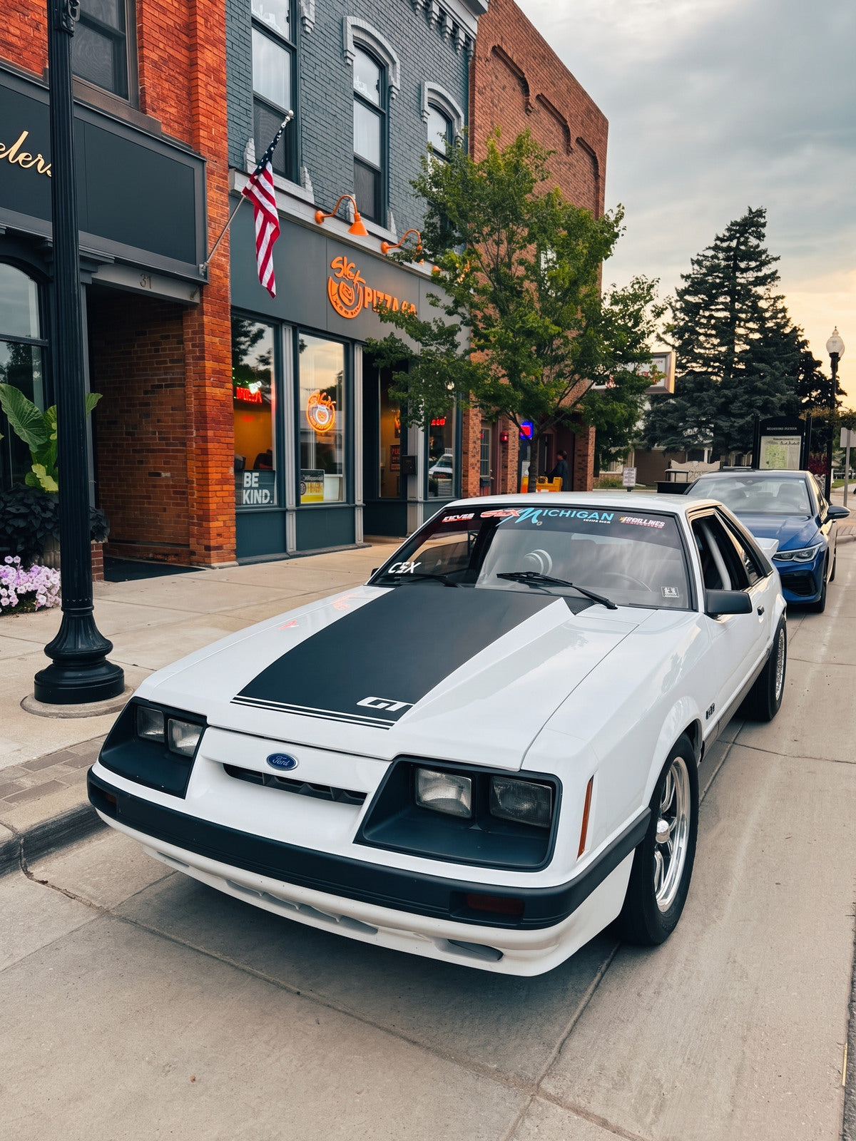 A white Ford Mustang parked along a downtown street.